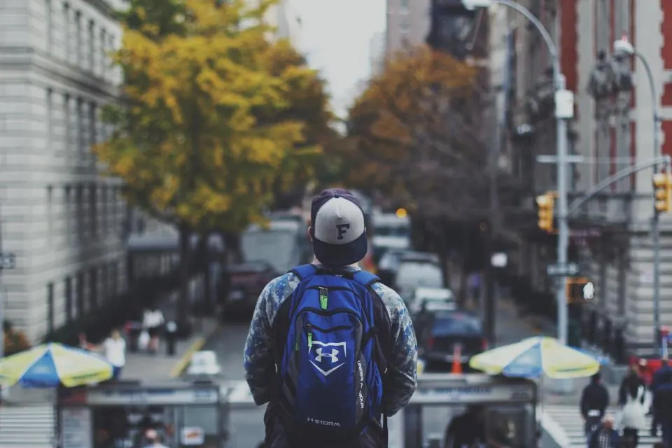 Un voyageur de dos, sac sur les épaules, dans une rue