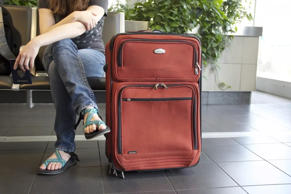Une voyageuse attend, assise près de sa valise