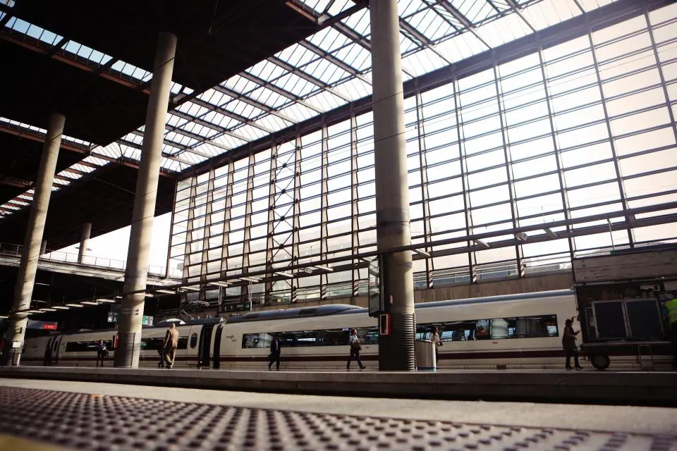 Le hall vitré d'une grande gare, des trains à quai