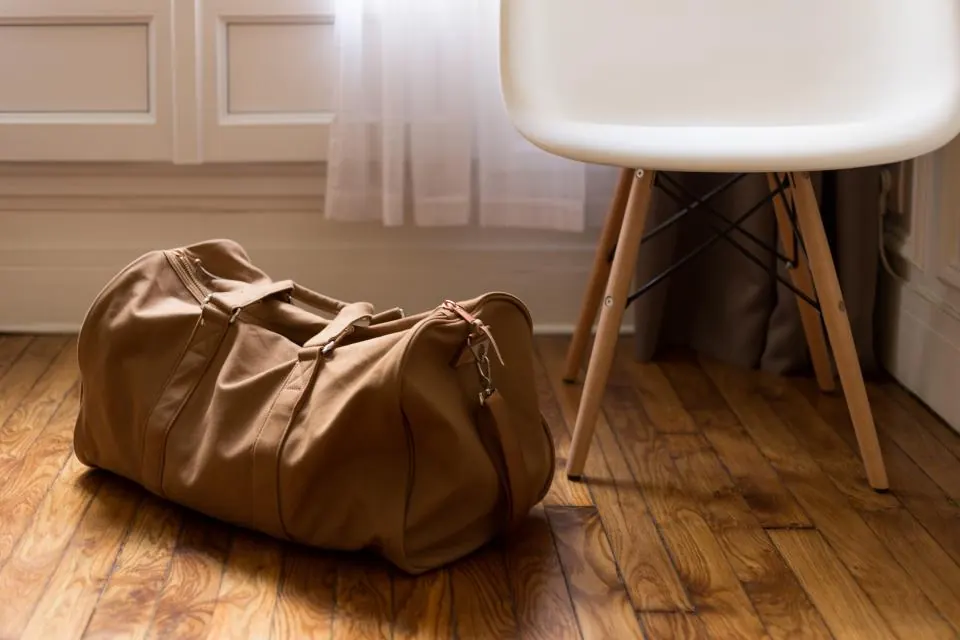 Un sac de voyage posé sur le parquet d'un logement tout juste investi
