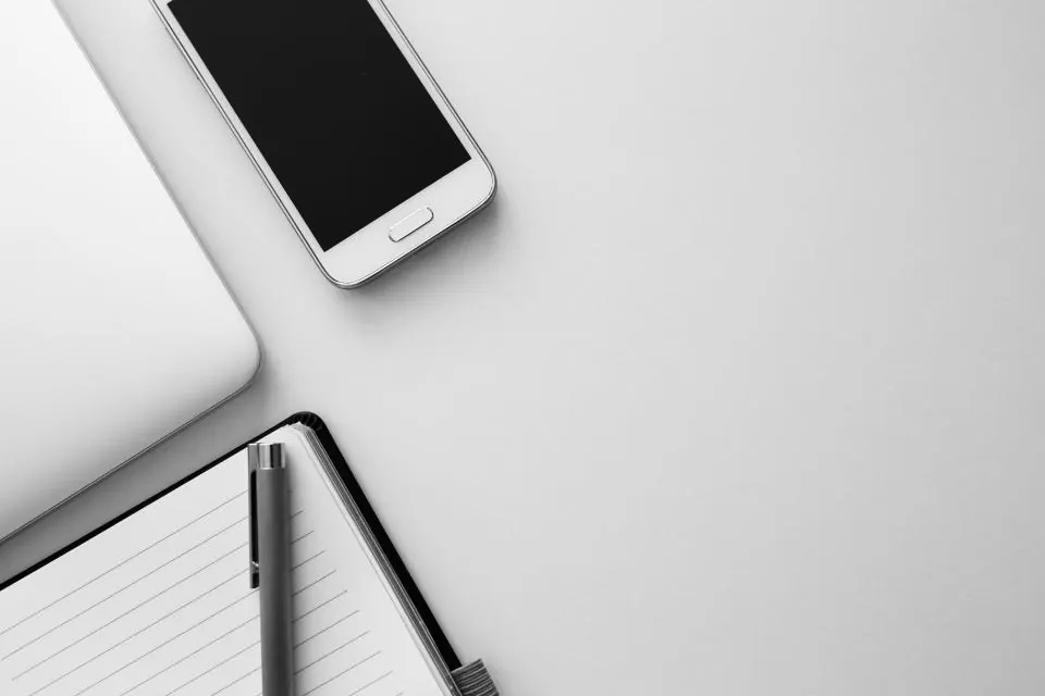 Un téléphone, un carnet et un ordinateur posés sur un bureau